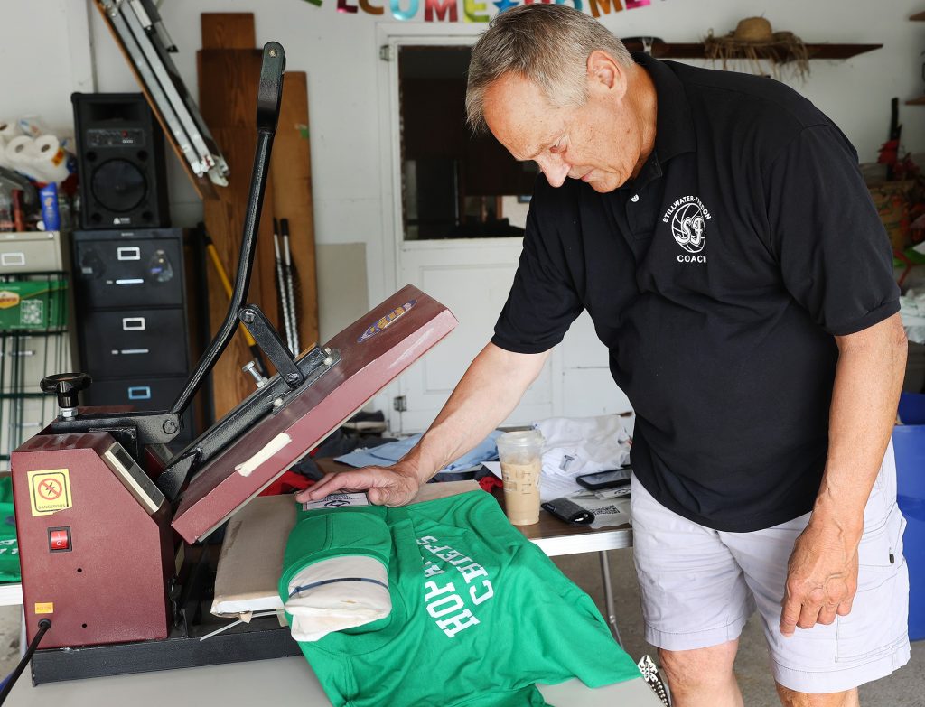 Paul Jetter uses a heat press to iron Safely Back Home ID decals onto shirts.
